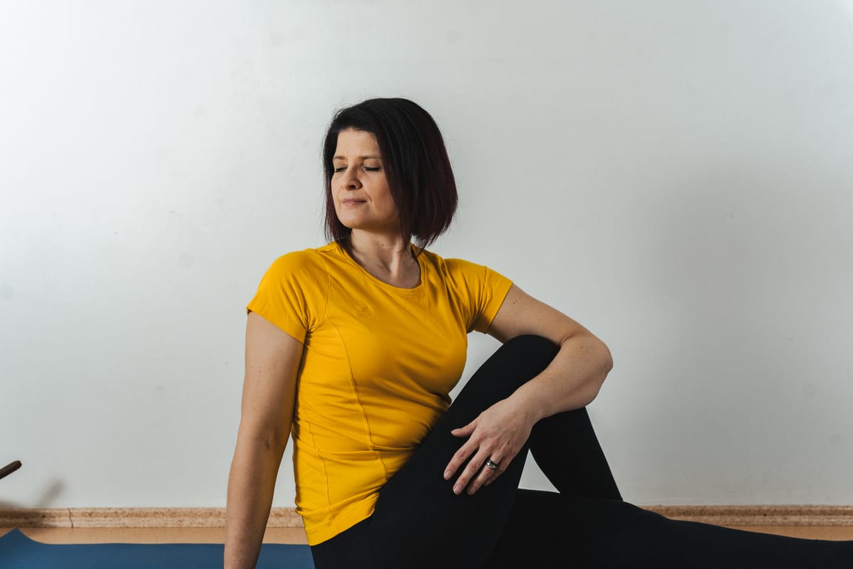 Kerstin Noack sitzt im Drehsitz auf einer Yogamatte