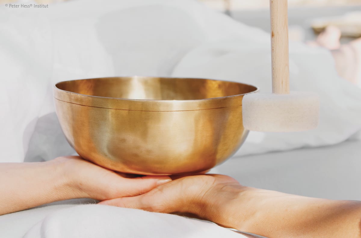 Offene Hände tragen eine goldene Klangschale, warmes Licht. Symbol für persönlichen Kontakt bei Klangherz Yoga